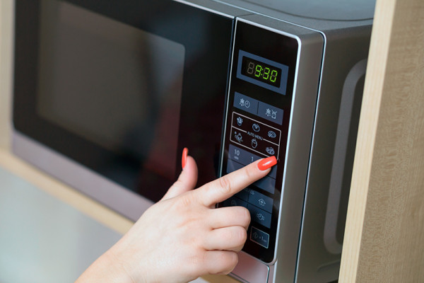 Female hand operating a microwave