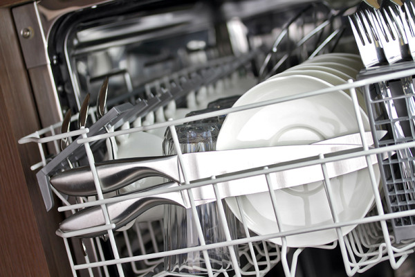 Closeup of a dishwasher with plates and utensils in the racks